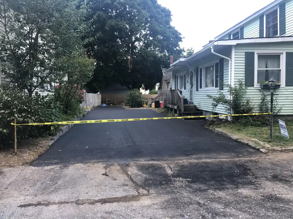 Driveway paving in Concord, NH: a freshly paved asphalt driveway beside a house, taped off at the street while it cures, Young's Excavating & Paving LLC, 37 Washington St, Penacook, NH.