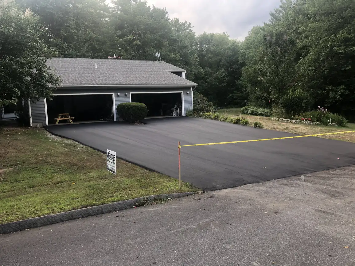 New asphalt driveway in Concord, NH in front of a two-car garage, taped off while it cures, Young's Excavating & Paving LLC, 37 Washington St, Penacook, NH.