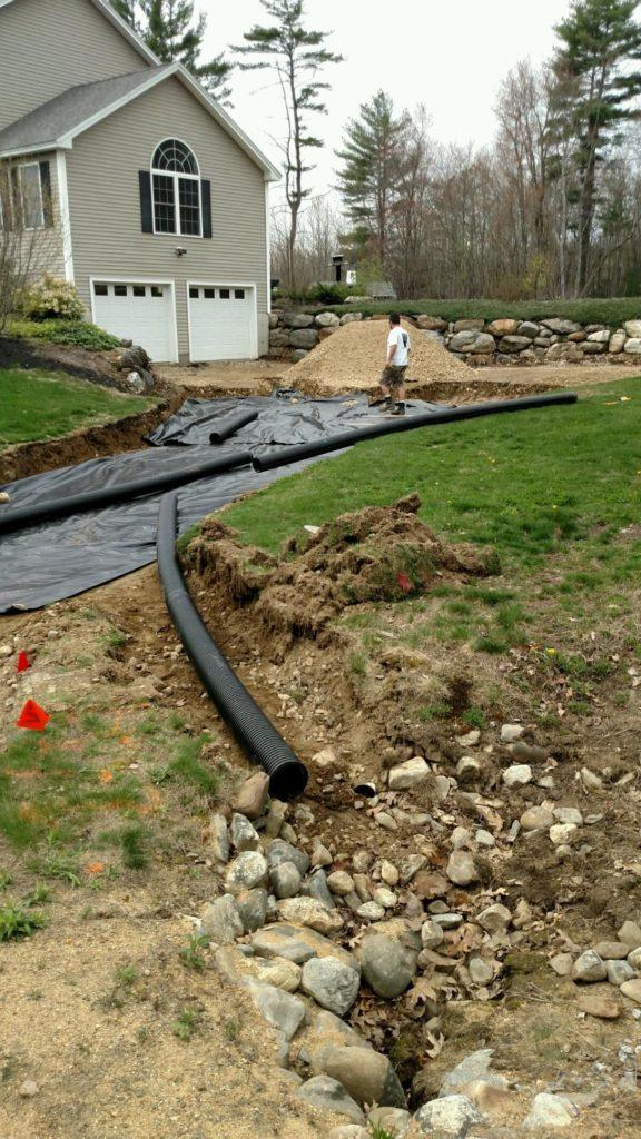 Corrugated drain pipe and a stone outfall going in beside a driveway before the base is built, Young's Excavating & Paving LLC, 37 Washington St, Penacook, Concord, NH.