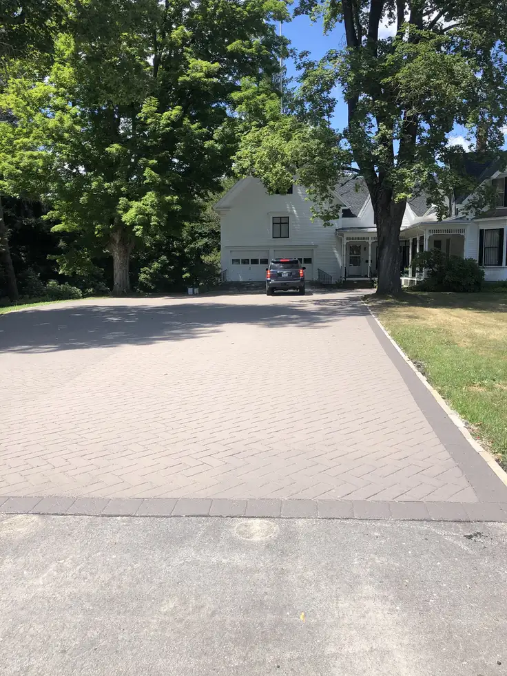 Stamped asphalt driveway in Concord, NH: a brick-pattern stamped asphalt driveway leading to a house with an attached garage, Young's Excavating & Paving LLC, 37 Washington St, Penacook, NH.