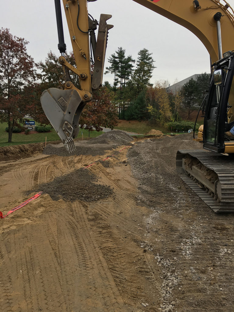 Young's CAT excavator grading and preparing a commercial site with crushed stone base in New Hampshire