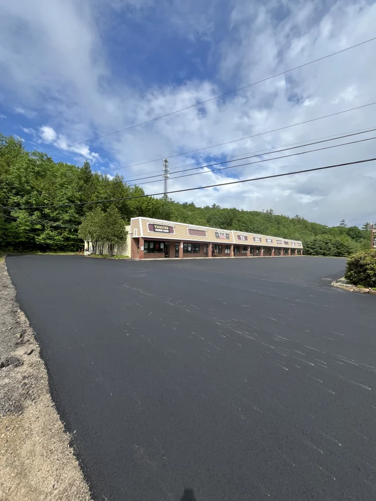 Looking across the new asphalt surface of the reclaimed parking lot at 680 White Mountain Highway in Tamworth, New Hampshire, toward the strip mall, Young's Excavating & Paving LLC, 37 Washington St, Penacook, NH.